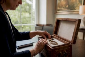 Hands unlocking wooden strongbox with heirloom ring